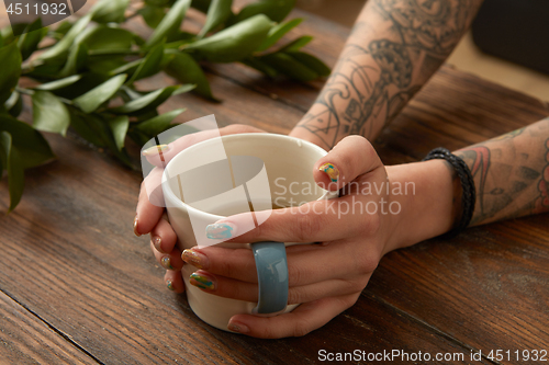 Image of Female hands holding coffee cup