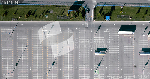 Image of Aerial view of a drone with a truck in the parking lot next to a green lawn and the reflection of shadows from street lamps on a sunny day.