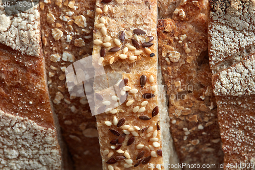 Image of Crispy organic bread slices with flax seeds and sesame macro photo. Flat lay