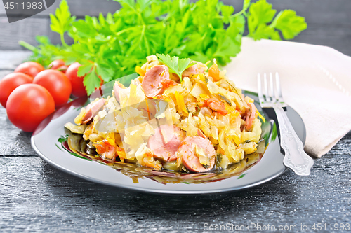 Image of Cabbage stew with sausages in plate on wooden board