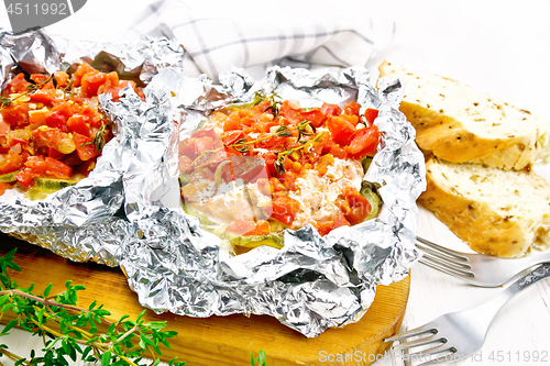 Image of Salmon with vegetables in foil on white board