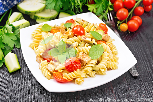 Image of Fusilli with chicken and tomatoes in plate on board