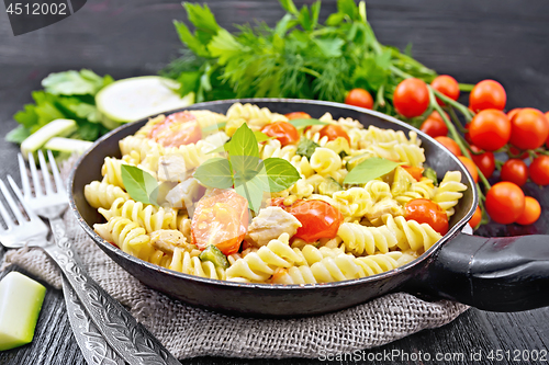 Image of Fusilli with chicken and tomatoes in pan on dark board