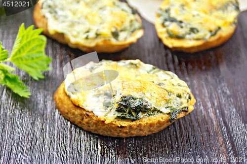 Image of Sandwich of nettle and cheese on dark wooden board