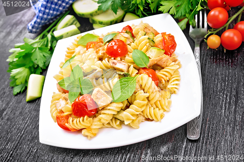 Image of Fusilli with chicken and tomatoes in plate on dark board