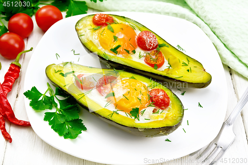 Image of Scrambled eggs with tomatoes in avocado on white wooden board