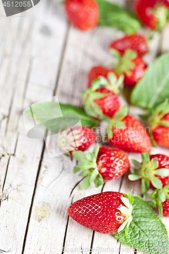 Image of Fresh red strawberries and mint leaves on rustic wooden backgrou