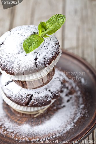 Image of Fresh chocolate dark muffins with sugar powder and mint leaf on 