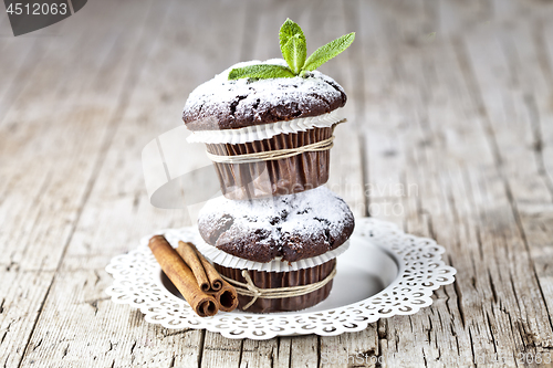 Image of Chocolate dark muffins with sugar powder, cinnamon sticks and mi