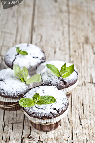 Image of Fresh chocolate dark muffins with sugar powder and mint leaf on 