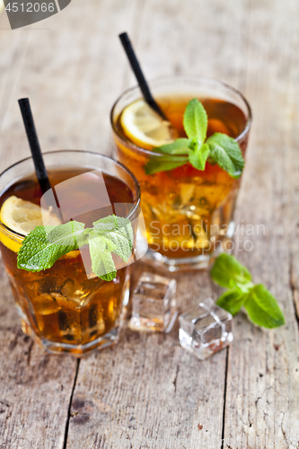 Image of Traditional iced tea with lemon, mint leaves and ice cubes in tw