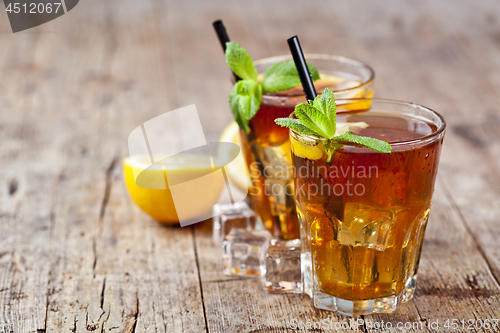 Image of Traditional iced tea with lemon, mint leaves and ice cubes in tw