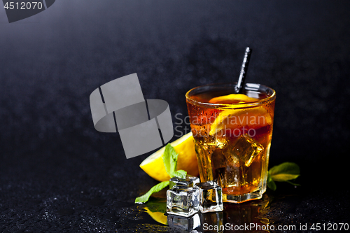 Image of Traditional iced tea with lemon, mint leaves and ice cubes in gl