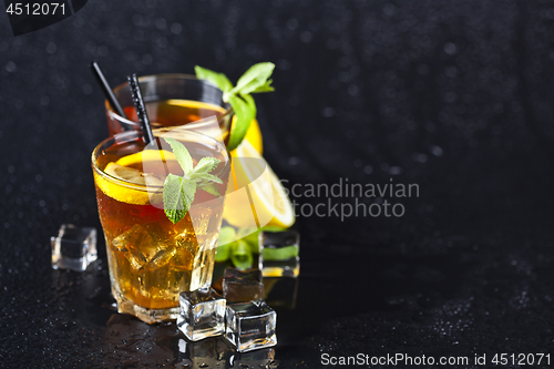 Image of Traditional iced tea with lemon, mint leaves and ice cubes in tw