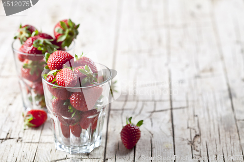 Image of Organic red strawberries in two glasses on rustic wooden backgro