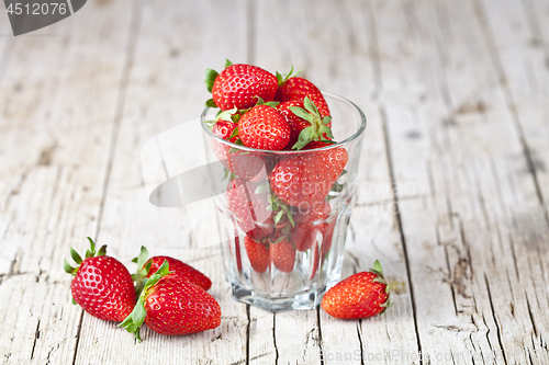 Image of Fresh red strawberries in glass on rustic wooden background.