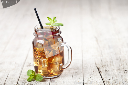Image of Traditional iced tea with lemon, mint leaves and ice cubes in gl