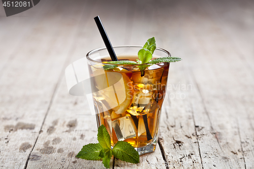 Image of Traditional iced tea with lemon, mint leaves and ice cubes in gl