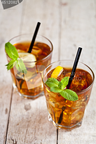 Image of Traditional iced tea with lemon, mint leaves and ice cubes in tw