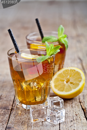 Image of Traditional iced tea with lemon, mint leaves and ice cubes in tw