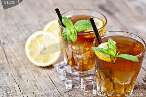 Image of Traditional iced tea with lemon, mint leaves and ice cubes in tw