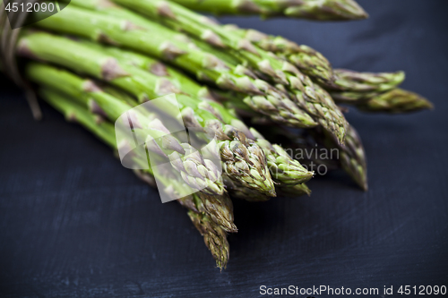 Image of Bunch of fresh raw garden asparagus closeup on black board backg