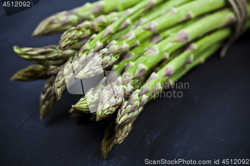 Image of Bunch of fresh raw garden asparagus closeup on black board backg
