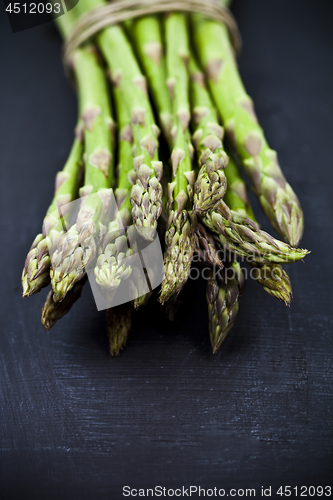 Image of Bunch of fresh raw garden asparagus closeup on black board backg