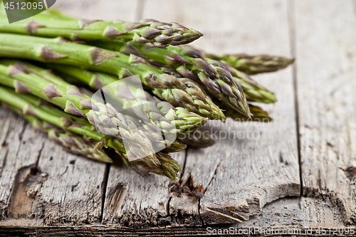 Image of Bunch of fresh raw garden asparagus closeup on rustic wooden tab