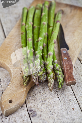 Image of Fresh raw garden asparagus and knife closeup on cutting board on