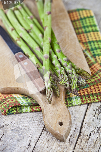 Image of Fresh raw garden asparagus and knife closeup on cutting board on