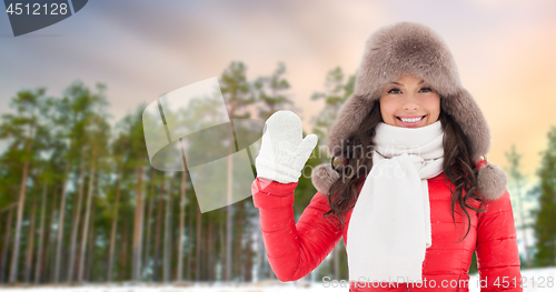 Image of happy woman in hat waving hand over winter forest