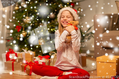 Image of smiling girl in santa hat with christmas gift