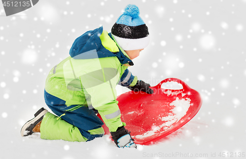 Image of happy boy with snow saucer sled in winter