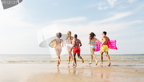 Image of friends run with beach ball and swimming mattress