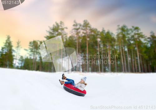 Image of happy teenage girl sliding down hill on snow tube