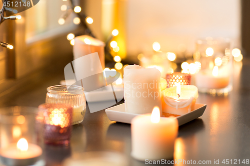 Image of candles burning on window sill with garland lights