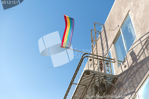 Image of gay pride rainbow flag waving on building balcony