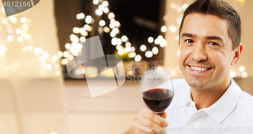 Image of happy man drinking red wine at home on christmas