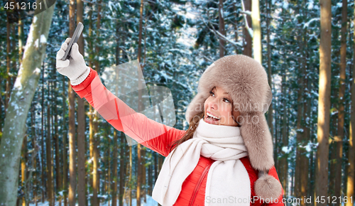 Image of happy woman taking selfie over winter forest