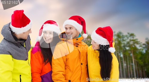 Image of friends in santa hats and ski suits on christmas