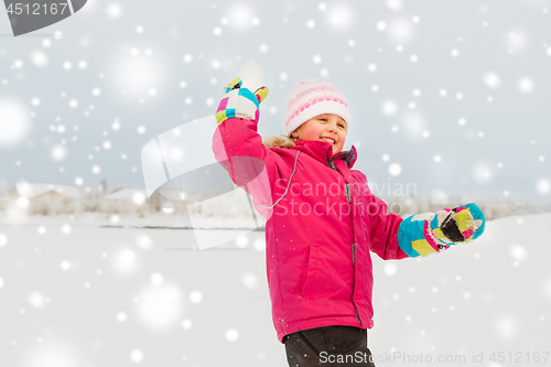 Image of happy girl playing and throwing snowball in winter