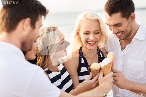 Image of happy friends eating ice cream on beach