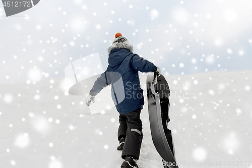 Image of little boy with sled climbing snow hill in winter