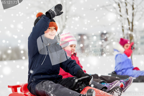 Image of happy kids sliding on sleds in winter