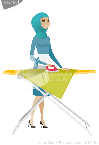 Image of Muslim maid ironing clothes on ironing board.