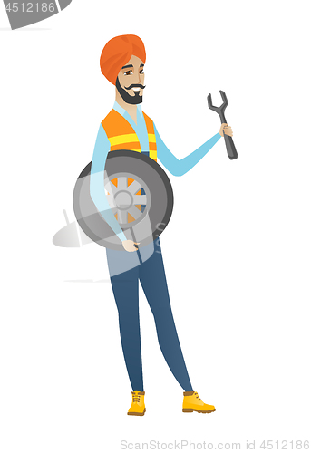 Image of Young hindu mechanic with tyre and spanner.