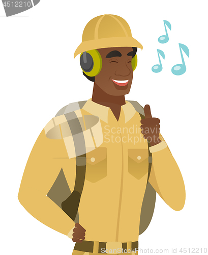 Image of African traveler listening to music in headphones.