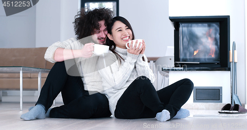 Image of multiethnic romantic couple  in front of fireplace