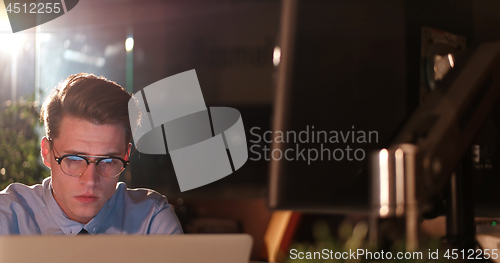 Image of man working on computer in dark office